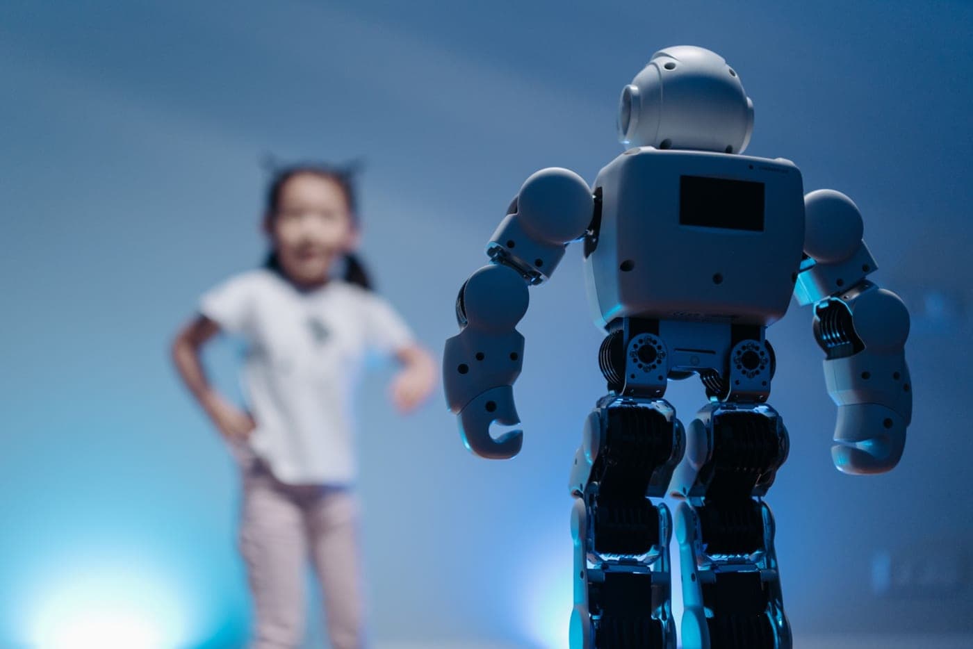 A humanoid robot standing in front of a child, illustrating how robots learn by observing people.