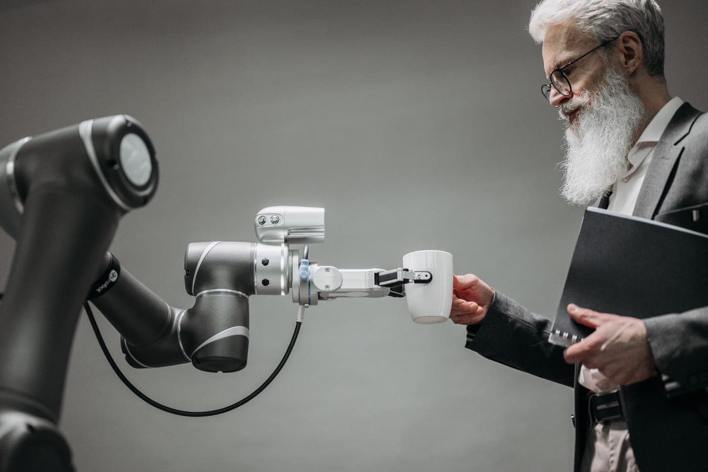 A robotic arm handing a coffee mug to a person, demonstrating precise real-world manipulation.