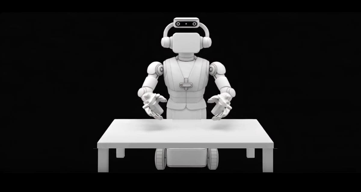 A white wheeled robot with two arms and a head-mounted camera standing behind an empty white table against a black background.