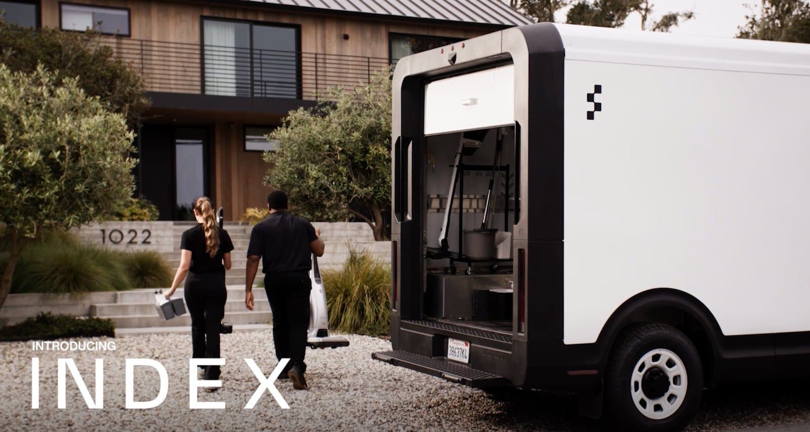 Figure AI's 'Introducing Index' image showing two people and a delivery pod outside a home.