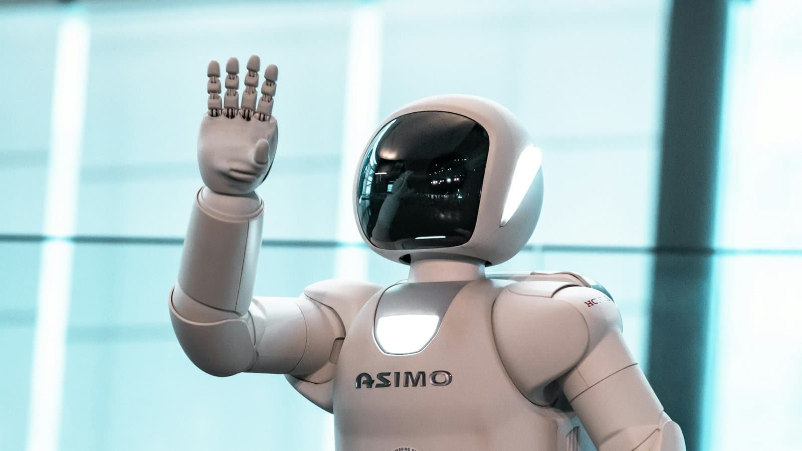 A white humanoid robot raising its hand, illustrating advances in humanoid robotics.