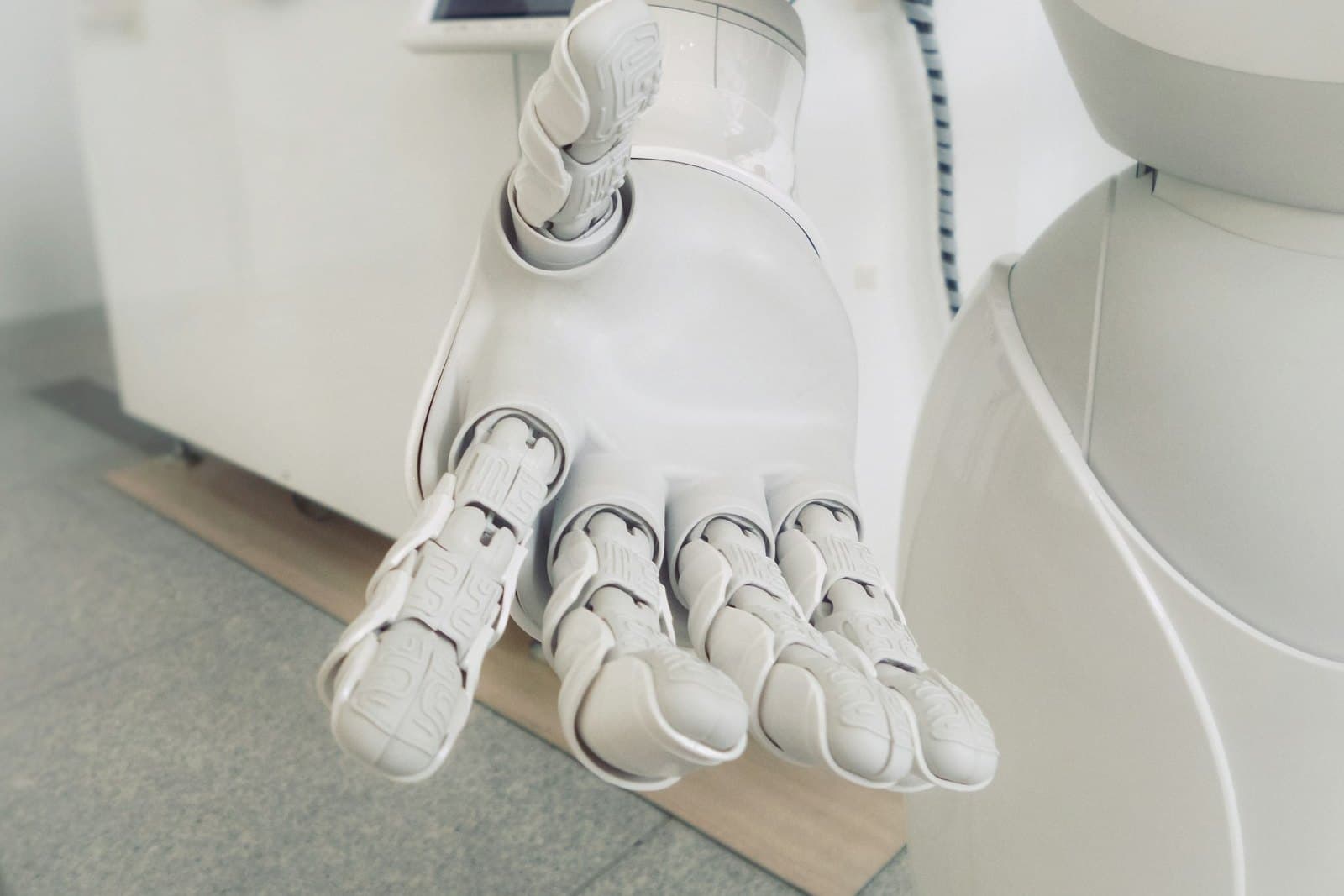 Close-up of a white humanoid robot's open hand with its fingers extended.