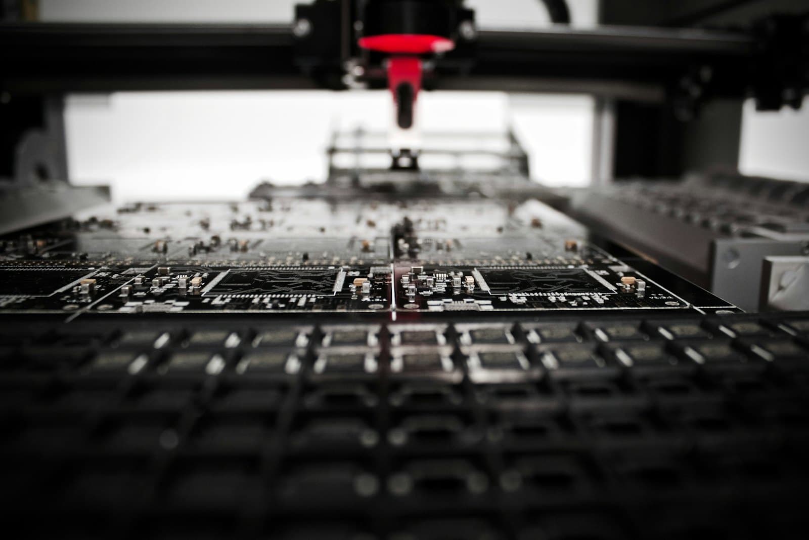 A robotic arm with a precision nozzle positioned above a circuit board in a lab.