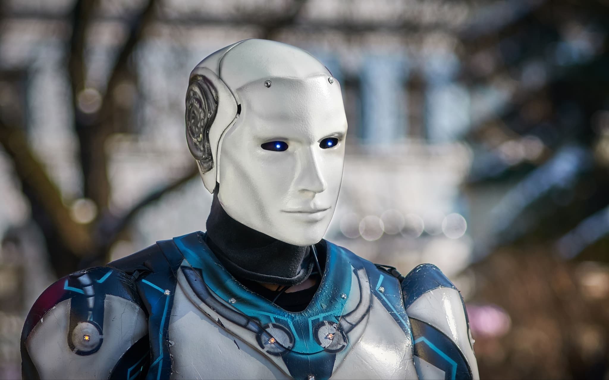 A humanoid robot with a human-like white face and blue sensor eyes.
