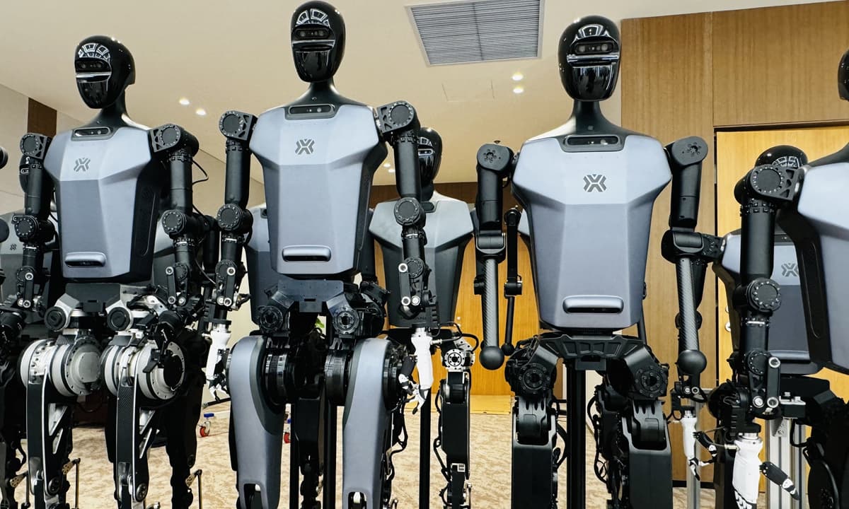 A row of general-purpose humanoid robots lined up in a room.