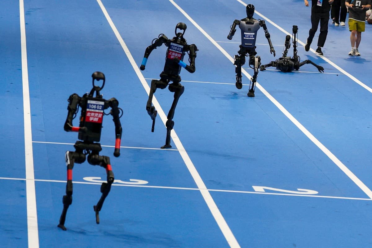 Humanoid robots racing on a track, with one fallen on the ground.